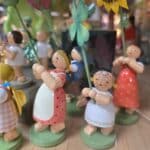 Mehrere bunte Holzfiguren mit Blumen, roten und weißen Kleidern und detailreich bemalten Gesichtern
