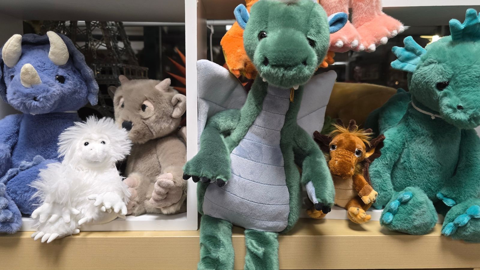 Mehrere Plüschtiere in verschiedenen Farben und Formen, darunter Drachen mit Flügeln und ein Tier mit weißem Fell